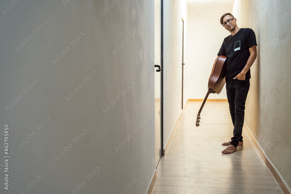 Confident musician holding guitar while standing in corridor Confident musician holding guitar while standing in corridor