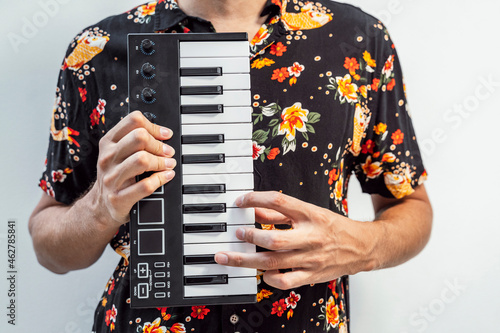 Man playing midi keyboard while standing against wall