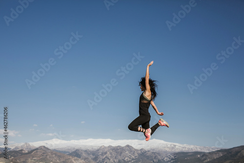 Woman jumping with Sierra Nevada background, Andalusia, Spain photo