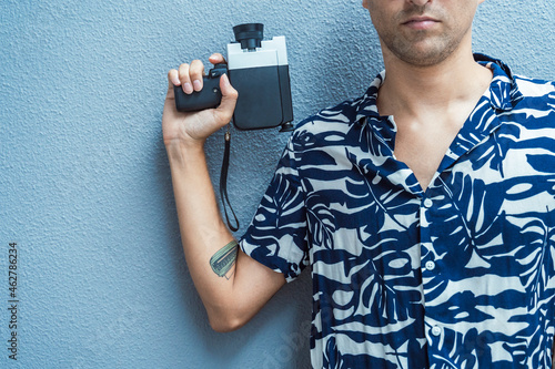 Man holding movie camera against blue wall photo