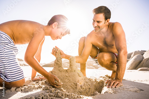 Father and son buliding sand castle on the beach together photo