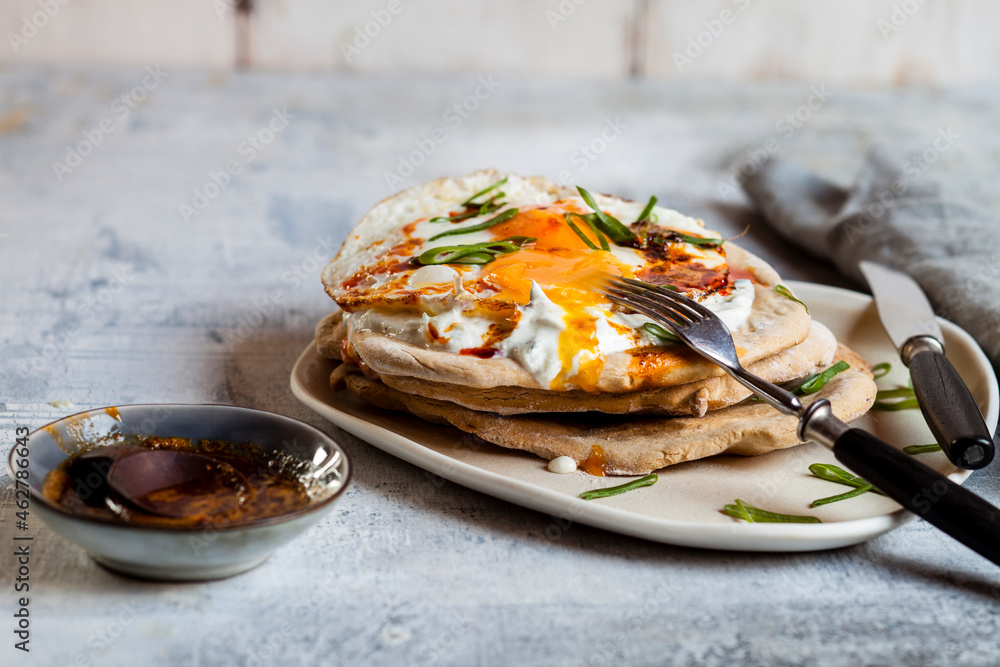 Flat bread with garlic yogurt, fried egg and chilli butter on chopping board Flat bread with garlic yogurt, fried egg and chilli butter on chopping board