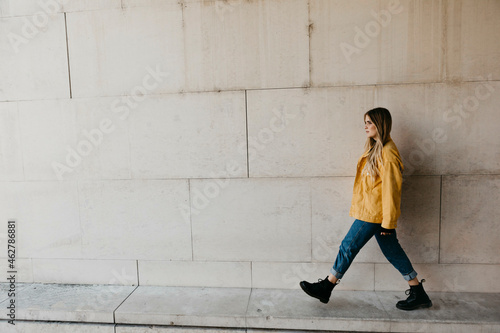 Walking young woman wearing yellow jacket