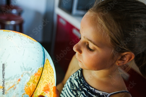 Curious girl looking at illuminated globe photo
