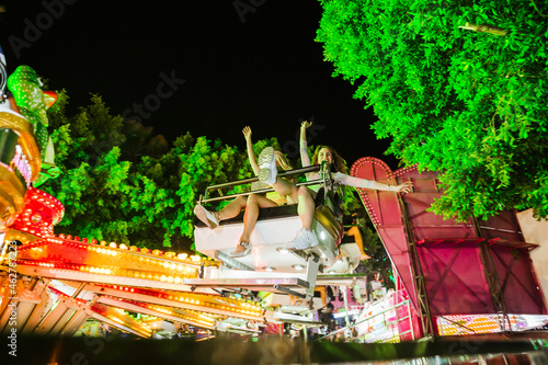 Two excited young women in a fairground ride on a funfair at night photo