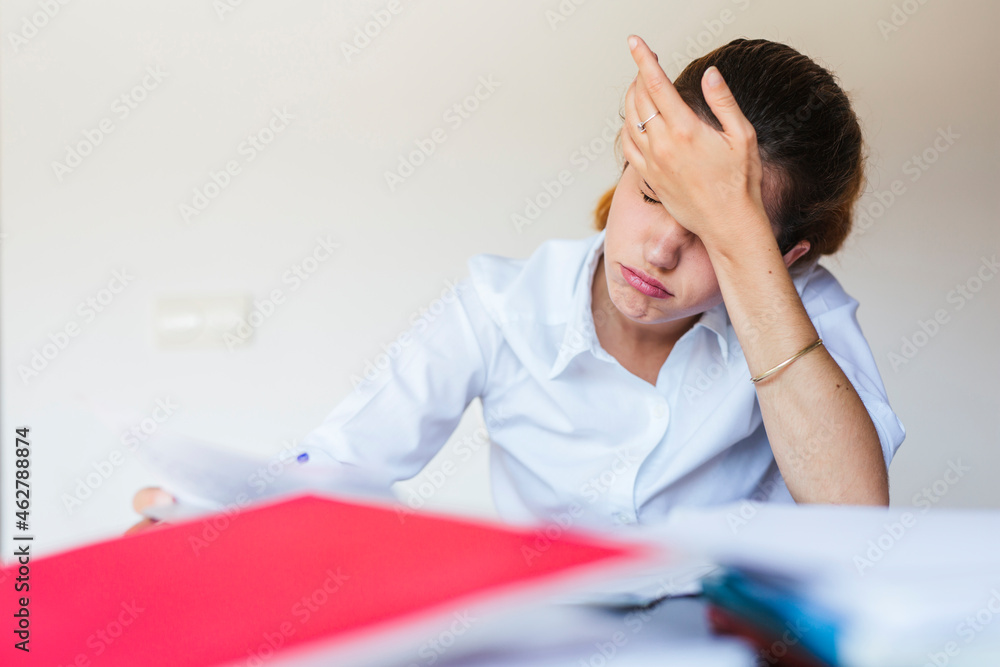 Frustrated female student with documents at desk at home Frustrated female student with documents at desk at home