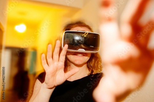 Close-up of woman gesturing while looking through virtual reality simulator at home photo