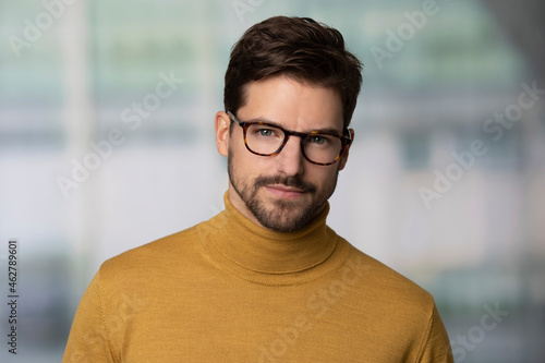 Portrait of confident man wearing glasses and yellow sweater photo