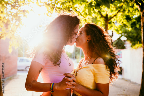 Romantic lesbians kissing while standing in city on sunny day