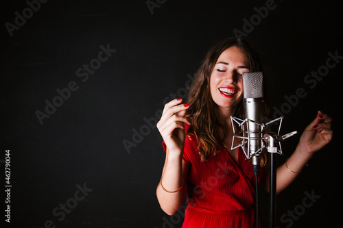 Portrait of female singer with microphone, wearing red dress photo