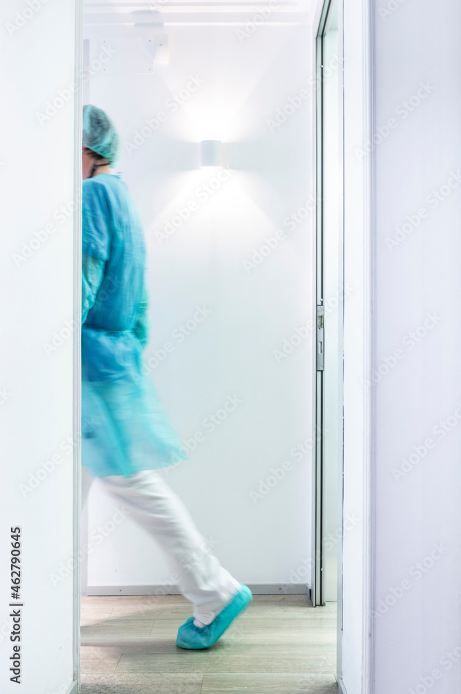 Mature male dentist walking in illuminated hallway Mature male dentist walking in illuminated hallway