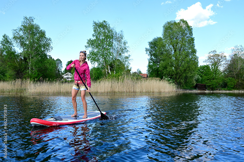 Woman stand up paddling on Lake Staffelsee, Bavaria, Germany Woman stand up paddling on Lake Staffelsee, Bavaria, Germany