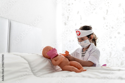 Girl in doctor's costume caring of her doll with a mask