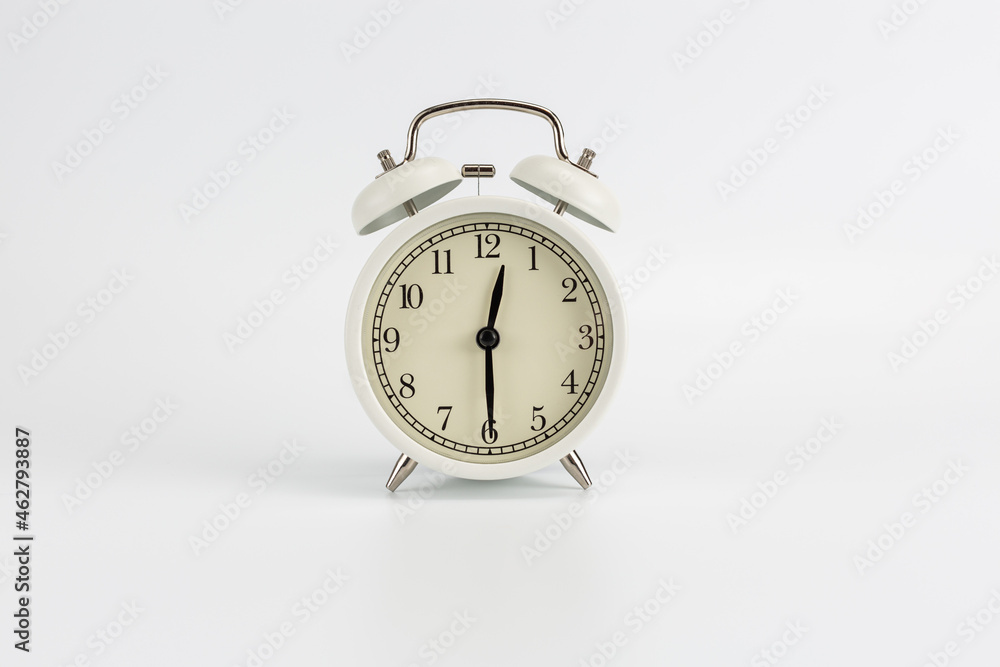 White retro clock alarm clock on white background shows 12:30 am or 12:30 pm or 00:30 White retro clock alarm clock on white background shows 12:30 am or 12:30 pm or 00:30