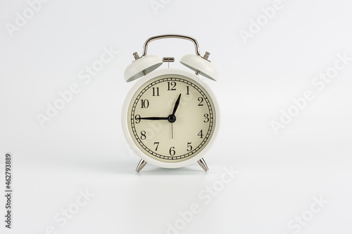 White retro clock alarm clock on white background shows 12:45 am or 12:45 pm or 00:45