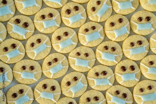 Rows of Christmas cookies with faces wearing protective face masks photo