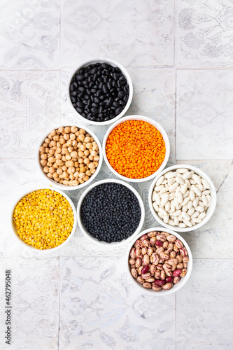 Various legumes in bowls: chickpeas, cannellini beans, quail beans, black beans, yellow lentils, red lentils, black lentils photo