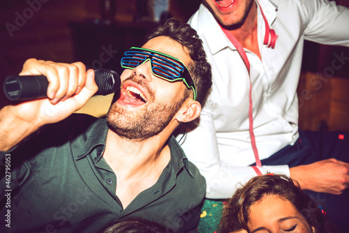Close-up of young man singing karaoke while enjoying with friends in party
