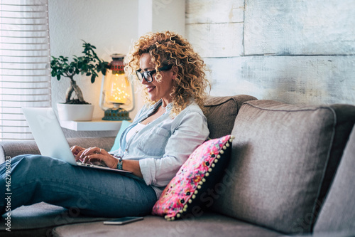 Smiling woman using laptop on couch at home photo