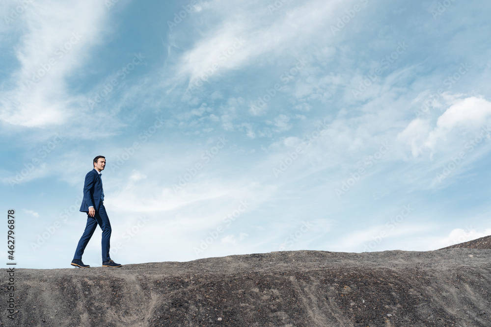 Mature businessman walking on a disused mine tip Mature businessman walking on a disused mine tip