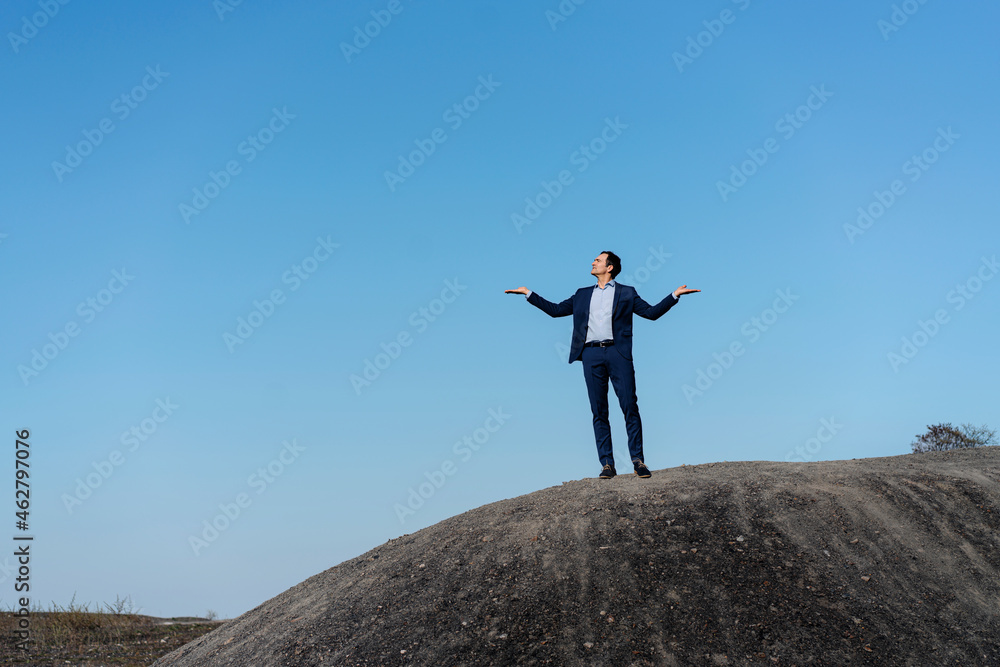 Mature businessman standing on top of a disused mine tip Mature businessman standing on top of a disused mine tip