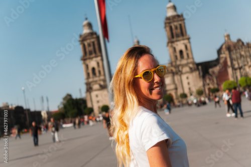 Smiling young woman wearing sunglasses while standing at Zocalo Square, Mexico photo