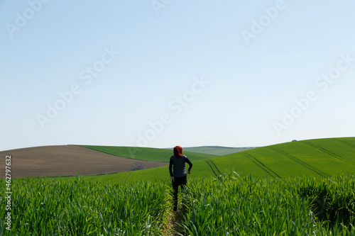 Mujer vista trasera disfrutando de un campo  verde vibrante sembrado en Andalucía, España photo