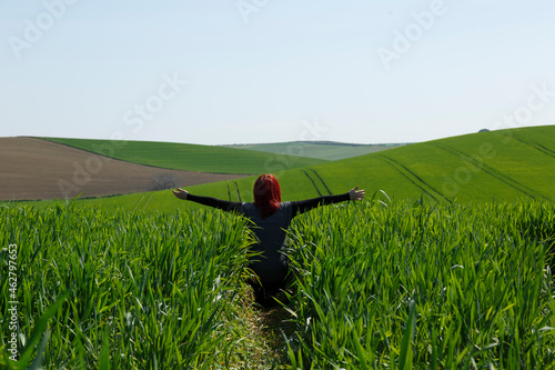 Mujer vista trasera disfrutando de un campo  verde vibrante sembrado en Andalucía, España photo