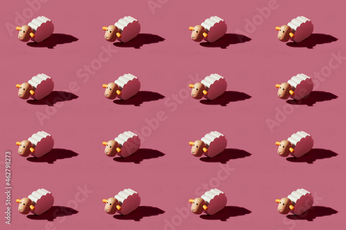 Pattern of small white sheep figurines against red background photo