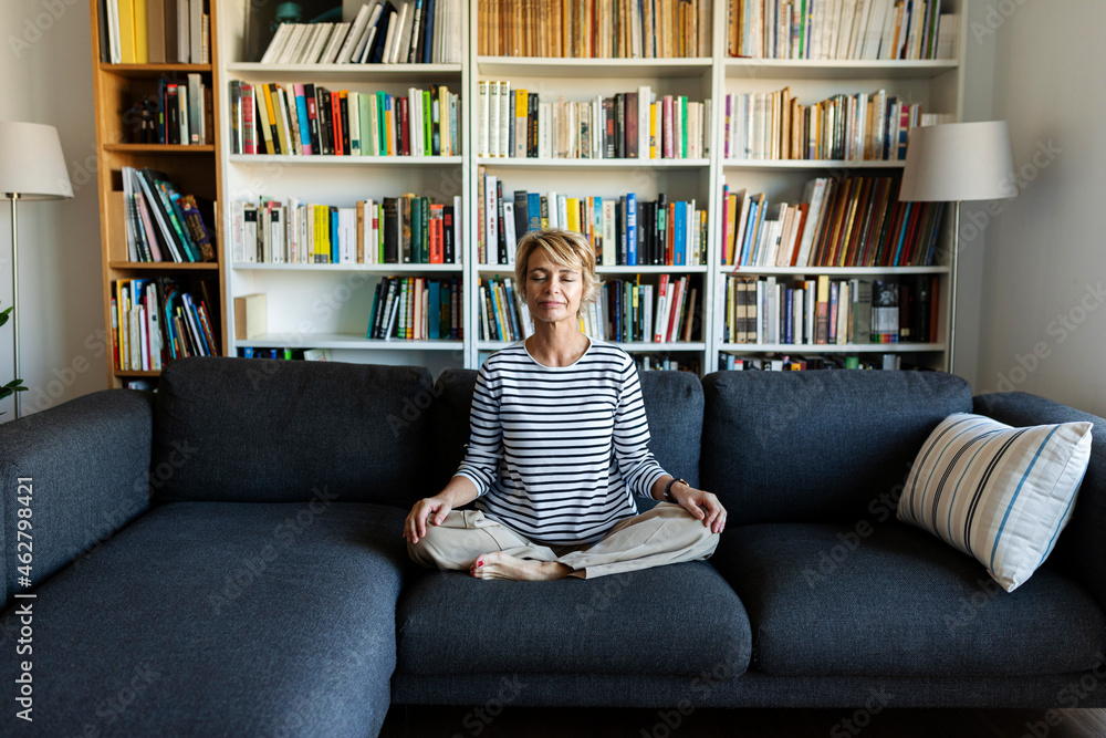 Mature woman practicing yoga on couch at home Mature woman practicing yoga on couch at home