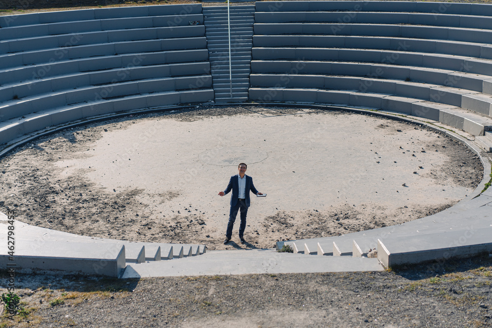 Mature businessman standing in an amphitheatre on a disused mine tip site Mature businessman standing in an amphitheatre on a disused mine tip site