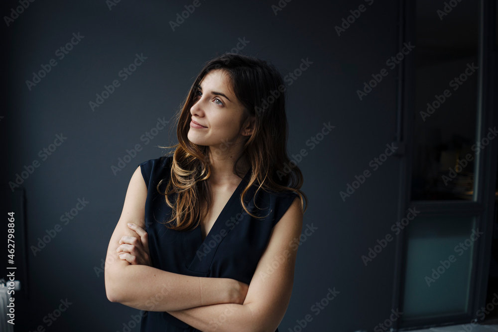 Portrait of smiling young woman with arms crossed against grey background Portrait of smiling young woman with arms crossed against grey background