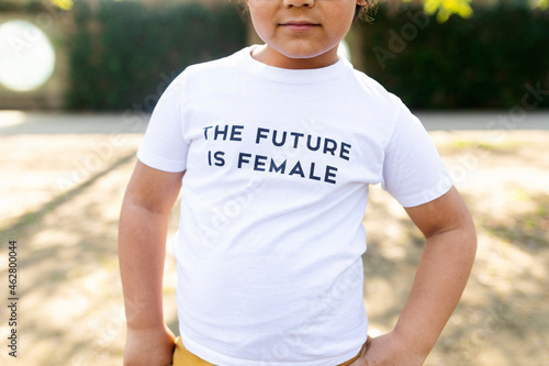 Proud little boy standing in the street with print on t-shirt, saying the future is female photo