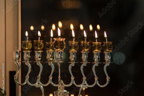 Hanukkah candles are lit in a silver-decorated menorah, against a black background of the night - the Jewish holiday of Hanukkah photo