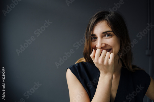 Portrait of laughing young woman with hand covering mouth photo