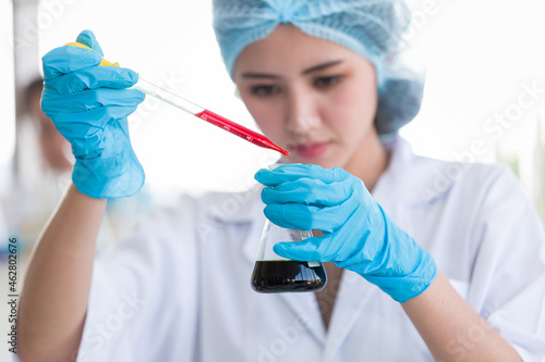 Asian female scientists wearing hairnet  glasses and gloves doing scientific experiment and analysis germs bacteria in laboratory. Female specialist. Researcher working at laboratory
