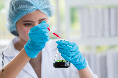 Asian female scientists wearing hairnet, glasses and gloves doing scientific experiment and analysis germs bacteria in laboratory. Female specialist. Researcher working at laboratory