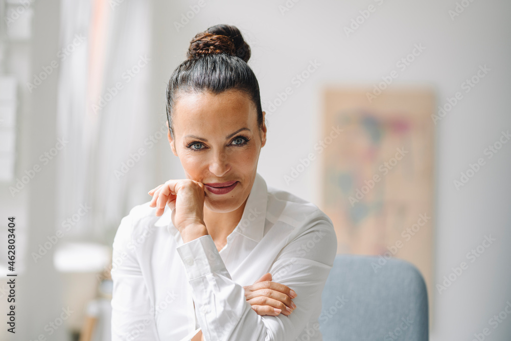 Close-up of smiling female professional sitting in home office Close-up of smiling female professional sitting in home office