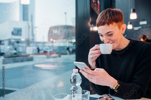 Redheaded young woman using smartphone in a cafe photo