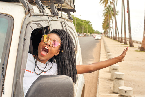 Portrait of screaming woman with dreadlocks leaning out of car window, Maputo, Mozambique photo