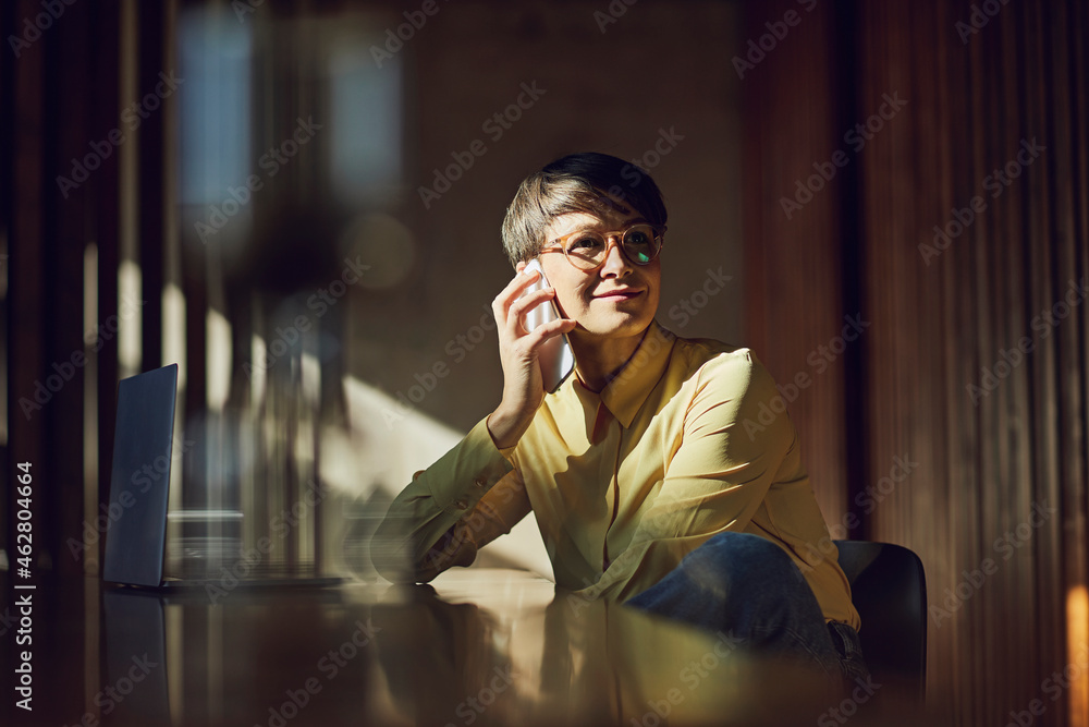 Businesswoman sitting in her sustainable office, talking on the phone Businesswoman sitting in her sustainable office, talking on the phone