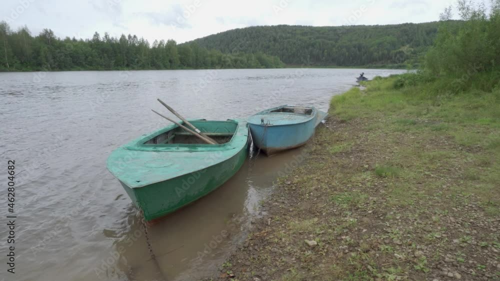 Three fishing traditional Russian boats moored on the bank of the Vishera river in the wild