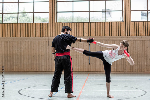Female kickboxer sparring with coach in sports hall photo