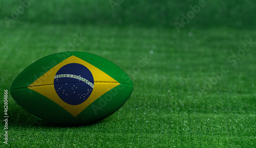American football ball  with Brazil flag on green grass background  close up