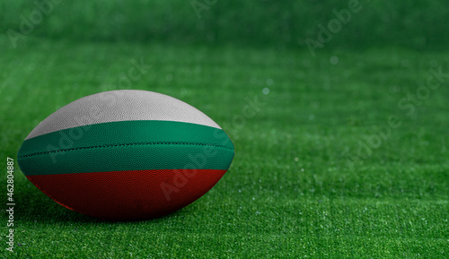 American football ball with Bulgaria flag on green grass background, close up