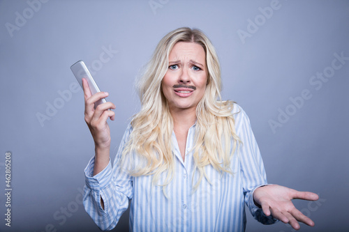 Portrait of asking blond woman with fake moustache and smartphone photo