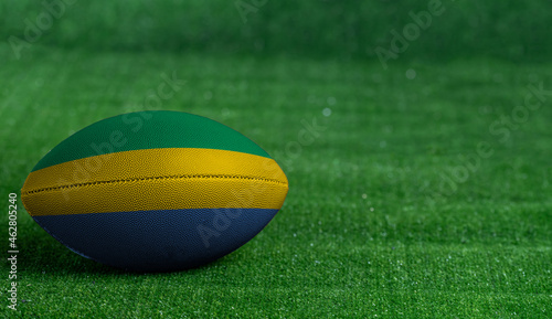 American football ball with Gabon flag on green grass background, close up