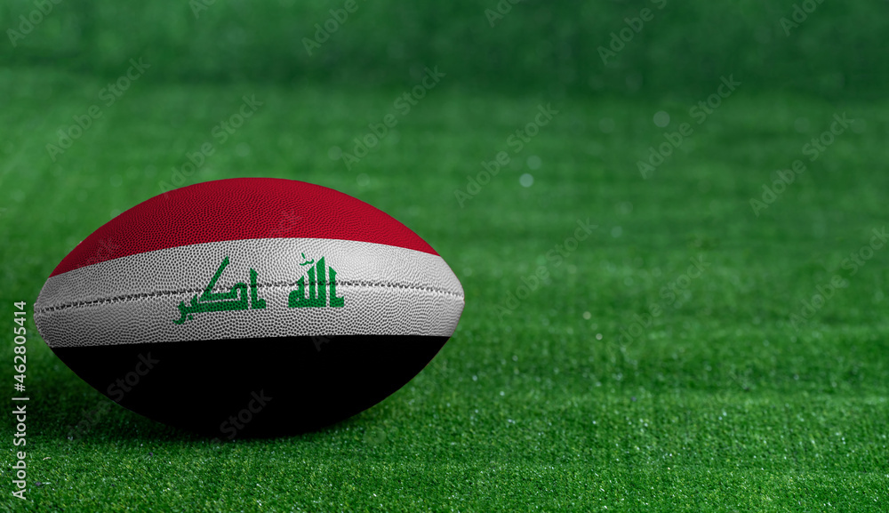 American football ball with Iraq flag on green grass background, close up American football ball with Iraq flag on green grass background, close up