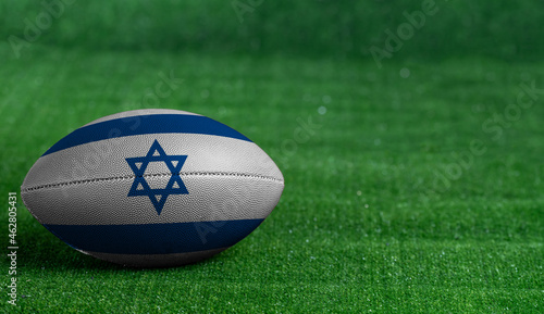 American football ball with Israel flag on green grass background, close up