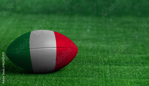 American football ball  with Italy flag on green grass background  close up